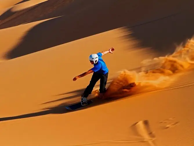 Sandboarder riding down a sand dune
