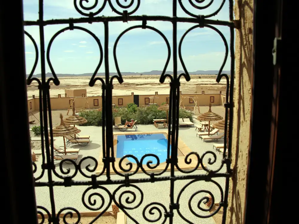 The riad pool seen through a traditional wrought-iron window