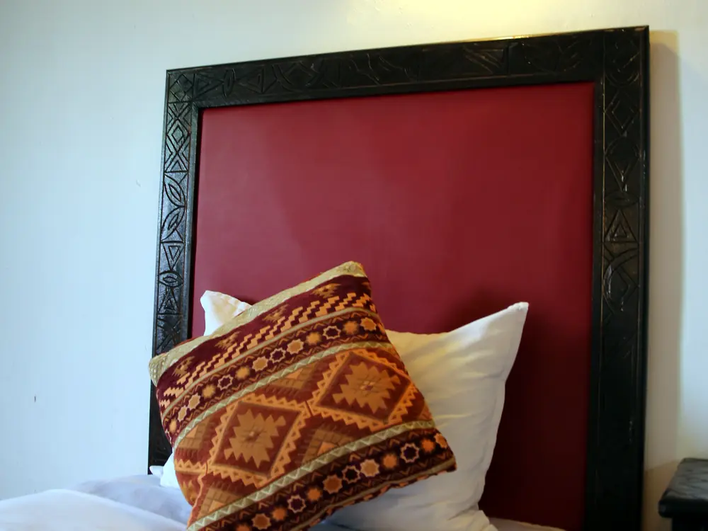 Single bed with red headboard and wall lamp